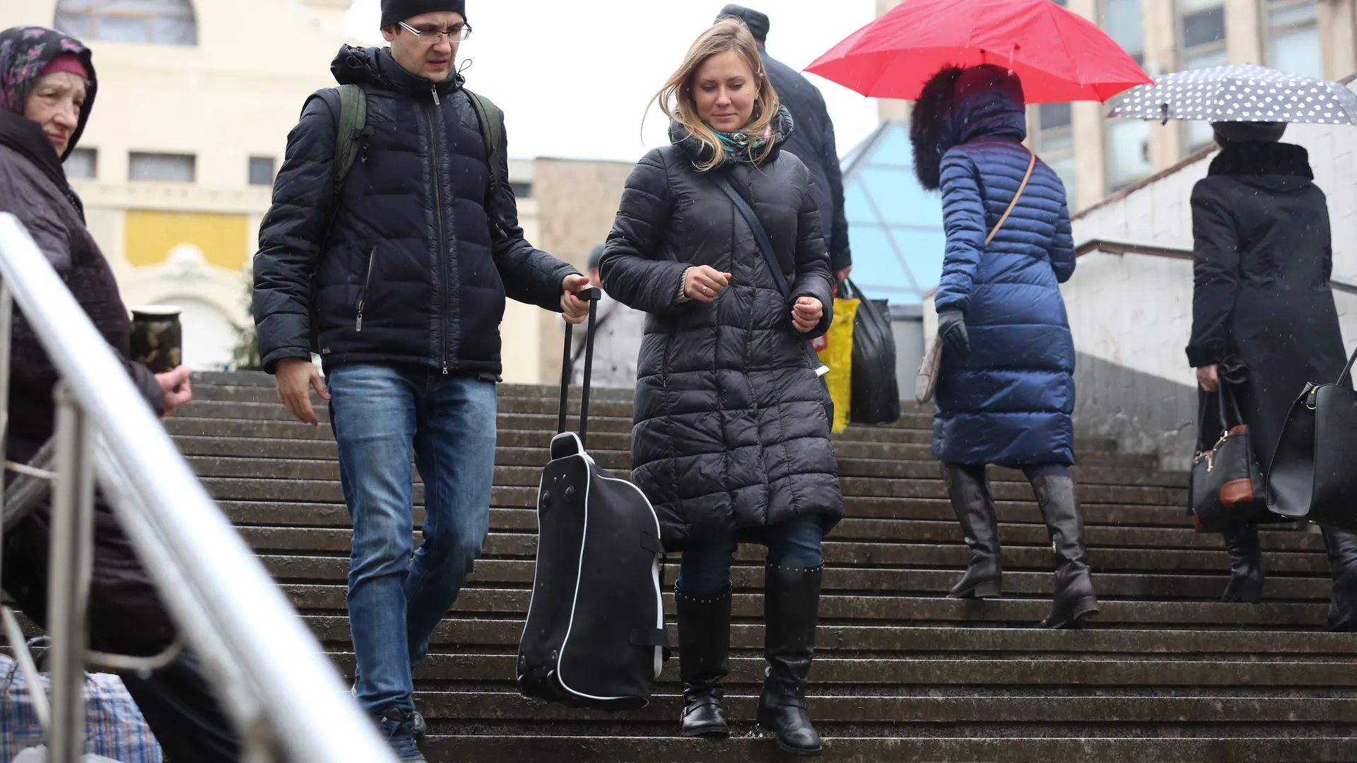 Мужчина помогает девушке спустить чемодан